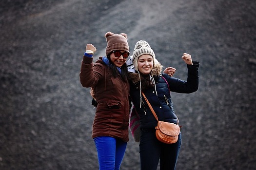 Two girls wearing winter coats and hats doing fist pump