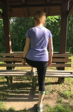 A picture of Amy stepping up on a park bench