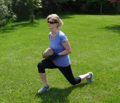 A picture of Amy doing lunges holding a large rock
