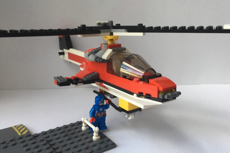 A picture of a Lego helicopter being lifted by a Lego Captain America