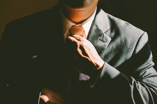 A picture of a man adjusting his tie and looking very confident