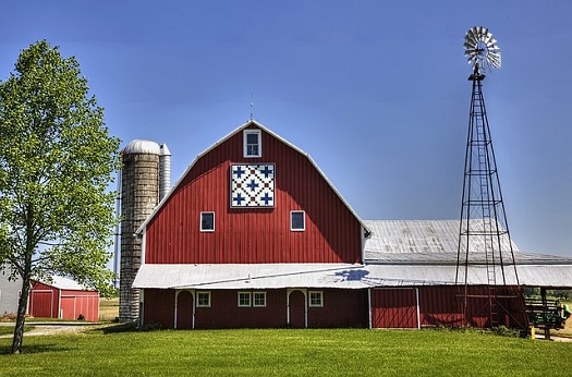 a picture of a barn with a silo and a windmill
